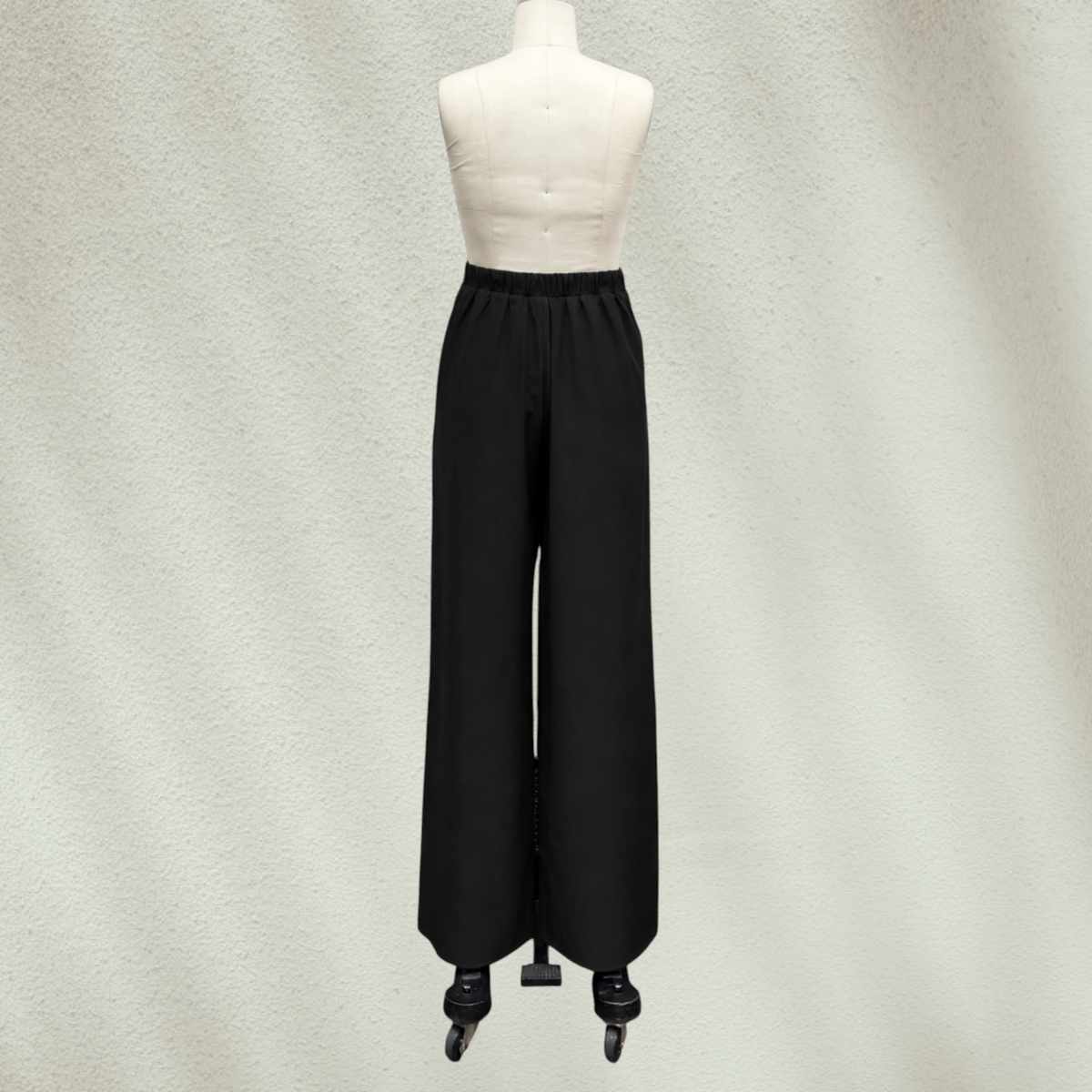Purple Lola's Block black high-waisted wide-leg pants on a mannequin, featuring a comfortable elastic back waistband.